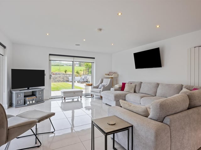 Sun lounge with tiled floor and twin PVC patio doors to rear garden and driveway.