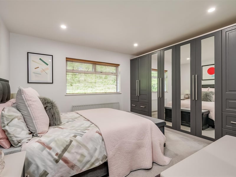 Principal bedroom with wall-to-wall fitted wardrobes and storage.