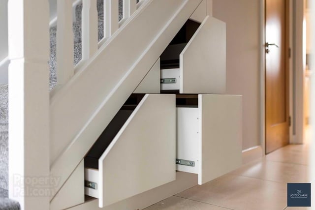 The hallway features useful storage drawers under the stairs.