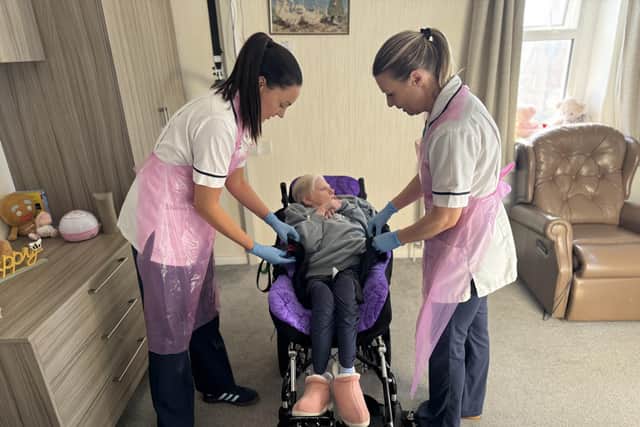 Caoimhe and Samantha help Elizabeth into her bespoke moulded wheelchair.