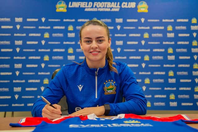Alex Clarke signing on the dotted line for Linfield FC Women.