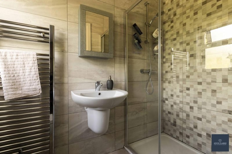 The fully tiled en suite bathroom features a  walk-in shower cubicle with mains-fed shower, floating sink, dual flush WC and a heated towel rail.