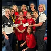 Sophia Woods (in yellow) of The Prom Friendship Group with the volunteer team, Mayor Gerardine Mulvenna and visitors, receiving a fundraising cheque.  Photo: Louise Magill