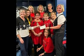 Sophia Woods (in yellow) of The Prom Friendship Group with the volunteer team, Mayor Gerardine Mulvenna and visitors, receiving a fundraising cheque.  Photo: Louise Magill
