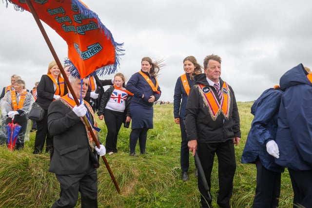 Orange men and women make their way through the dunes to the beach