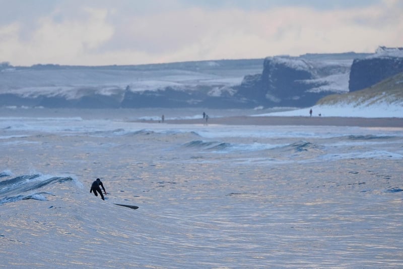 Cameron Leighton surfing with the snowy sand dunes of Portrush beach in the background