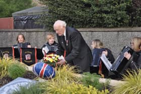 Roy Beggs MBE laying flowers at the NI Centenary Stone flowerbed.