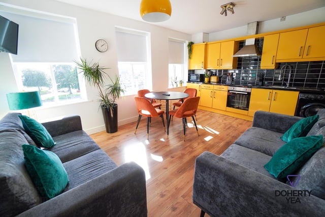 The kitchen/living area with laminate wood floor and painted high and low level units. The kitchen is plumbed for a washing machine and has a walk in store cupboard.