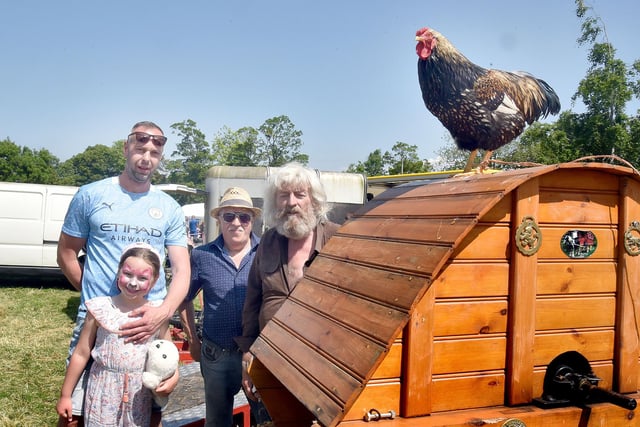 Guy the cockerel perches on a vintage threshing machine watched by from left, Matus and Liliana Baluga, Aidan O'Neill and Johnny Fee. PT23-228.