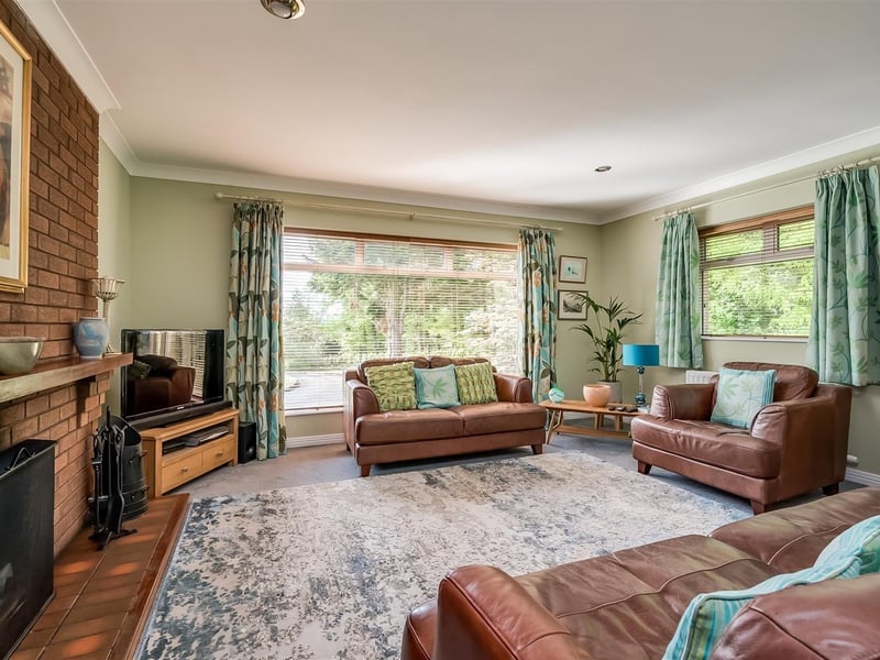 Lounge with open fire in brick fireplace and double glazed, sliding patio door to patio and side garden.