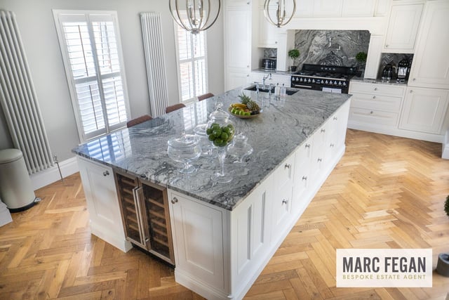 The stunning kitchen features a large island with granite worktop.