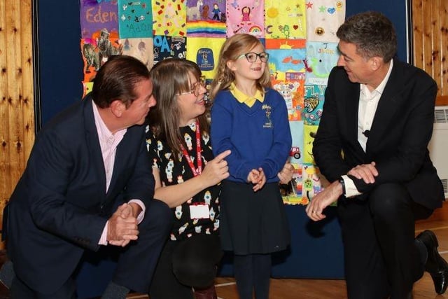 Co-founder Tony Carson and host Jim Fitzpatrick with a pupil and teacher from Carryduff-based Millennium IPS, in front of their winning artwork.