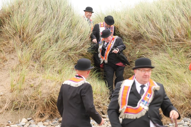 Orange men their way through the dunes to the beach