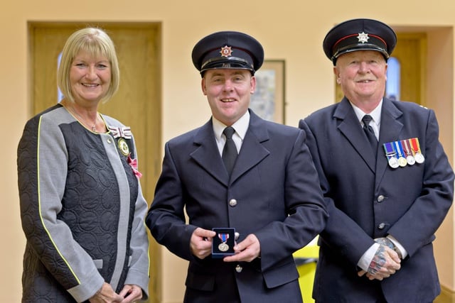 Firefighter Warren Logan at the presentation ceremony with Deputy Lieutenant for Co Antrim, Mrs Jackie Stewart MBE, and Watch Commander Brian Smith.