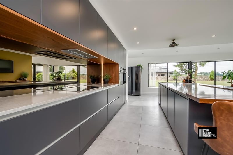Luxury fitted contemporary kitchen with comprehensive range of high and low level storage units with solid quartz work surface. The room also features a matching island unit with walnut breakfast bar area.