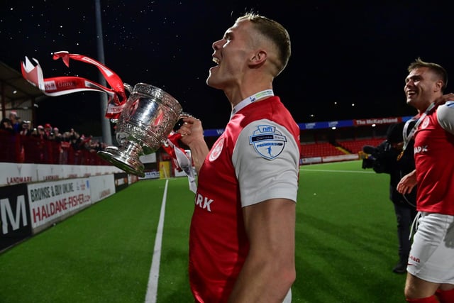 Larne player Leroy Miller shows off the Gibson Cup to the home fans.