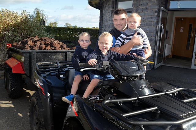 Twins Zach and Harry Beattie (3) posing on an ATV at the Annaghmore Parish HarvestFest with dad, James and baby brother, Jacob (1). PT42-203.