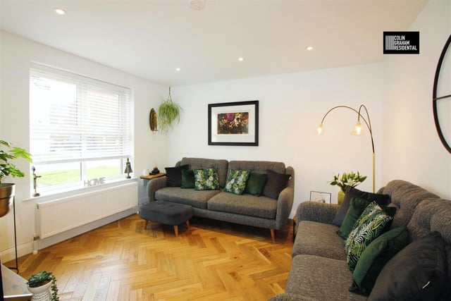 Lounge with engineered, herringbone timber flooring and picture window.