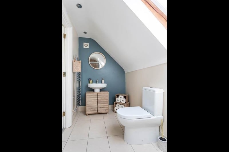 En-suite with heated towel rail, Velux window, spot lighting to ceiling and tiled flooring.