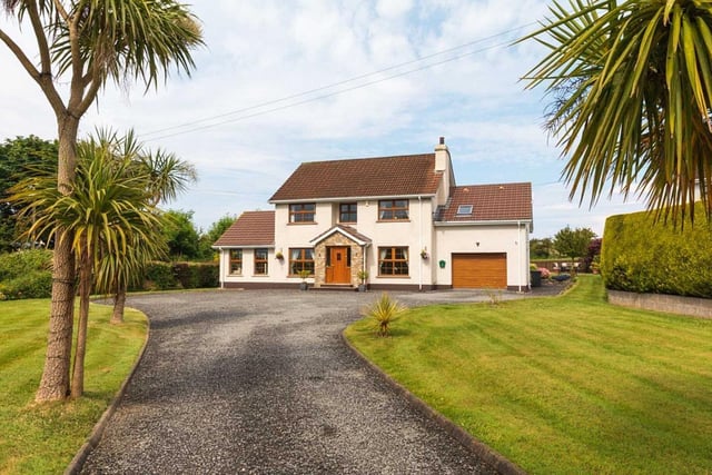 The property is approached by a sweeping stoned driveway flanked by spacious lawns.