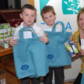 Ciara Burns, community energy worker with TADA gives reuseable bags and low wattage bulbs to St Mary's PS pupils Eoin McVeigh, Kevin O'Hagan and Danny McAllinden at the energy saving advice day in 2007.