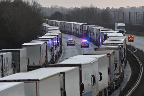 Police cars patrol as freight lorries and goods vehicles queue on a closed section of the M20 motorway which leads to the Port of Dover (Photo: JUSTIN TALLIS / AFP) (Photo by JUSTIN TALLIS/AFP via Getty Images)