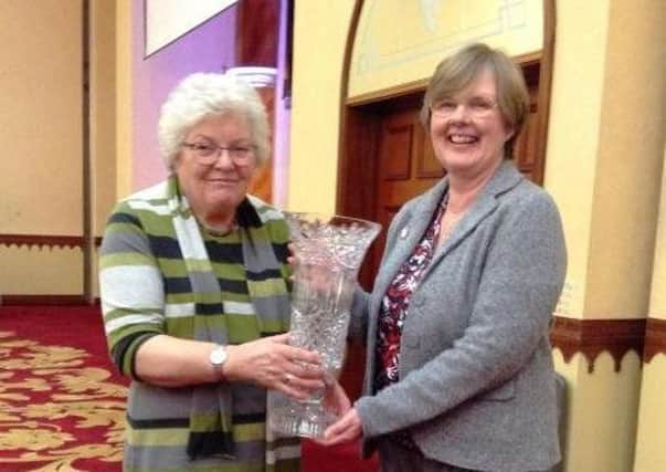 Mary Knox BEM, of Ballymena Floral Art,  is presented with The Ivan Watt MacMillan Trophy by Beverley Stephenson (NAFAS Area Judge)