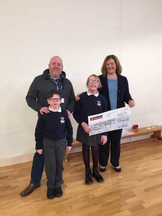 Johnny Reid, pictured with his nephew Matthew and fellow pupil Sarah, as he presents a cheque for Â£2,000 to Brookfield School principal Mrs Spence.