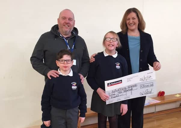 Johnny Reid, pictured with his nephew Matthew and fellow pupil Sarah, as he presents a cheque for Â£2,000 to Brookfield School principal Mrs Spence.