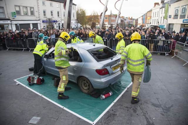 School pupils watch as paramedics and firefighters work together to safely remove the injured passenger from the car during a live road traffic collision demonstration in Lisburn city centre.
