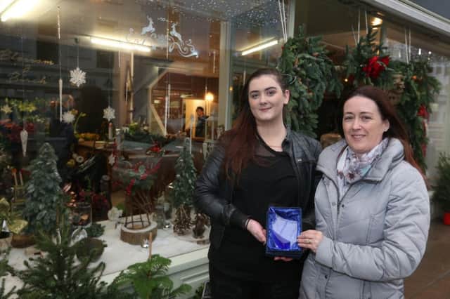 Shannon Ormandy from Blossom &  Birch receive her prize from Causeway Coast and Glens Borough Council Officer Catrina McNeill for coming third in the Christmas Window Competition.