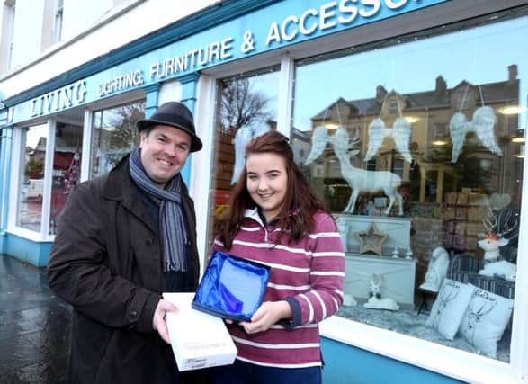 Grace Wilkinson accepts the prize on behalf of Patricia McNamara after her shop, Living Lighting, Furniture and Accessories was selected as the winner of the Christmas Window Competition in Ballycastle, organised by Causeway Coast and Glens Borough Councils Town Management team. Also included is Causeway Coast and Glens Borough Council Officer
Shaun Kennedy.
