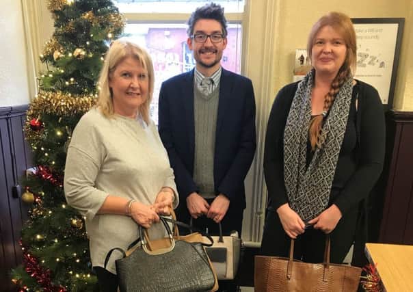 David McGuinness from Donaldson McConnell and Co Ltd presents the handbags to Siobhan Graham and Gemma Wilson from Womens Aid.