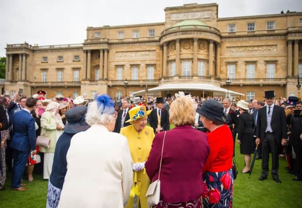 The Queen talks to guests during a garden party at Buckingham Palace in May last year
