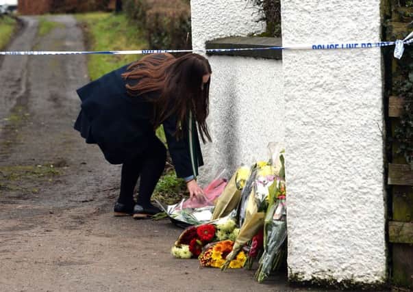 A schoolgirl adds to the floral tributes left outside the home of murder victim Robert Flowerday on Mill Road Road in Crumlin