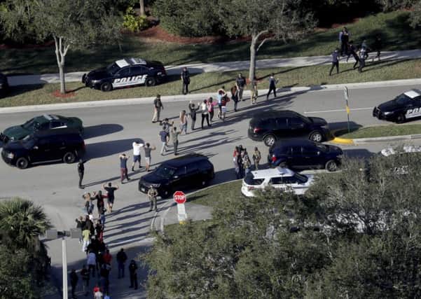 Students hold their hands in the air as they are evacuated by police from Marjory Stoneman Douglas High School in Parkland, Fla., on Wednesday, Feb. 14, 2018, after a shooter opened fire on the campus. (Mike Stocker/South Florida Sun-Sentinel via AP)