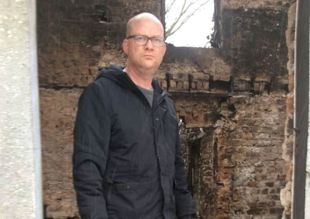 Sinn Fein Cllr Paul Duffy in the burnt out shell of a house which was attacked