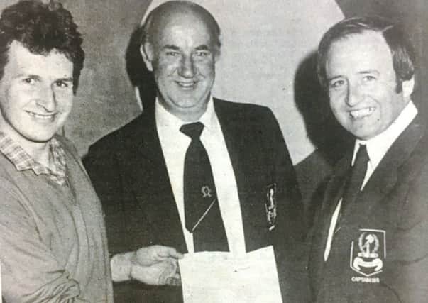 Fourteen Handicapper Ian Berry receives his Â£75 winners vouchers from Dunmurry Golf Club captain George Rodgers. Also included in the photograph from 1980 is Dunmurry Golf Club treasurer  Eddie Uprichard