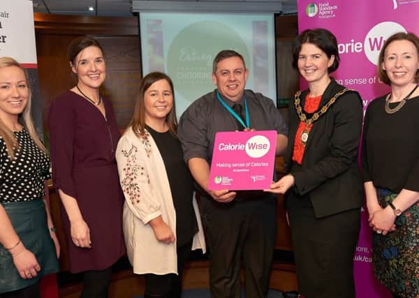 Mark Irvine, Support Services Manager at Mid Ulster Hospital, is pictured receiving his Calorie Wise Award from the Chair of Mid Ulster District Council, Councillor Kim Ashton. Also pictured, (l-r) are: Louise begs, Food Standards Agency; Monica Mc Donnell and Claire Mc Allister, Mid Ulster District Council and Fionnuala Close, Food Standards Agency.