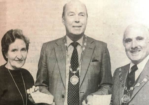 Mr Ian Lamb, president of Lisburn Chamber of Commerce, presents cheques for Â£100 to Mrs Laura Spier, joint secretary of Cancer Resaerch, and Alderman Samuel Semple for the Mayor's Appeal Fund in 1980.