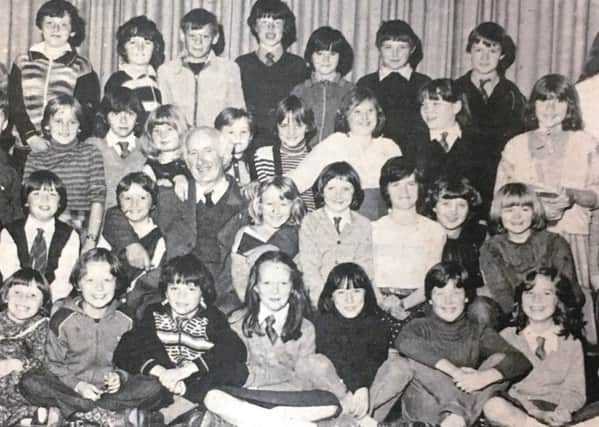 Mr Graham, caretaker at Lisburn Central Primary School, pictured with pupils to mark his retirement in 1980,