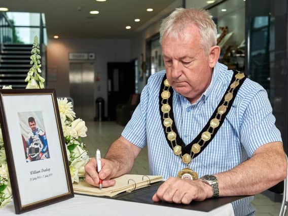Councillor Sean McPeake signs the Book of Condolence in memory of William Dunlop in the Burnavon, Cookstown