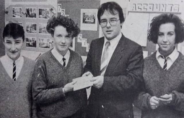 Gerry Ross of Allied Irish Bank who is financial adviser to Dunclug High Schools mini company - Prospects - hands over the company cheque book to company members. 1989
