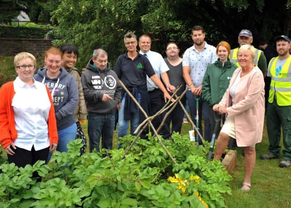 Getting ready to dig the spuds in the allotment is Councillor Audrey Wales as David McKay Base Co-ordinator and Helen Pidgeon Community Gardener Groundworks NI along with others look on.