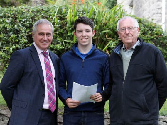 All smiles from Connor McCollam, with his father Paddy (right) and Mr J Brady, as he picks up his results, 1 A star and three A grades.