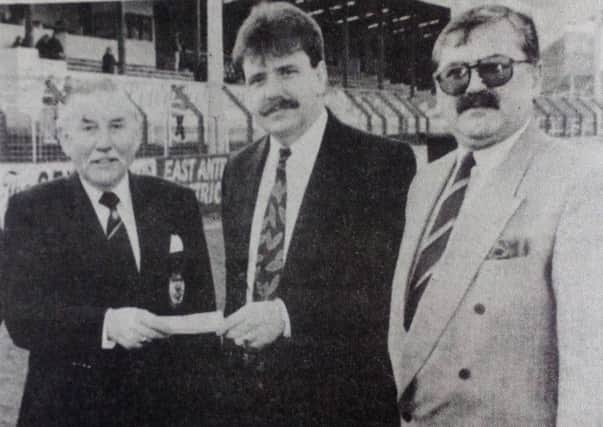 Ken Pritchard receives a cheque to sponsor Saturday's match from John Henry of the Market Bar, Ballyclare, as John Woods looks on, 1991.