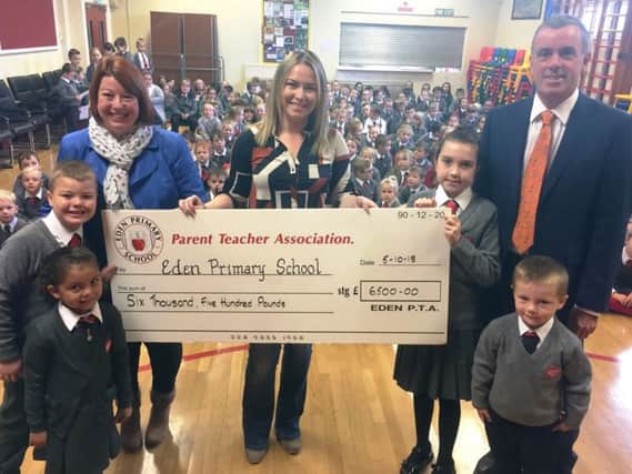 Sharon Gorman (left), chairperson and, Cathy McMurtry, previous chairperson, present pupils and Dr Sheeran, principal, with a cheque for Eden Primary School on behalf of the PTA.