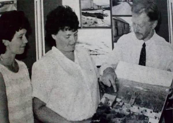 Cathy Knox, Tina Smith, Tony Stevens, and Margaret Craig examine a photograph of Glenarm at the draft Study Plan Exhibition in the village. 1989.