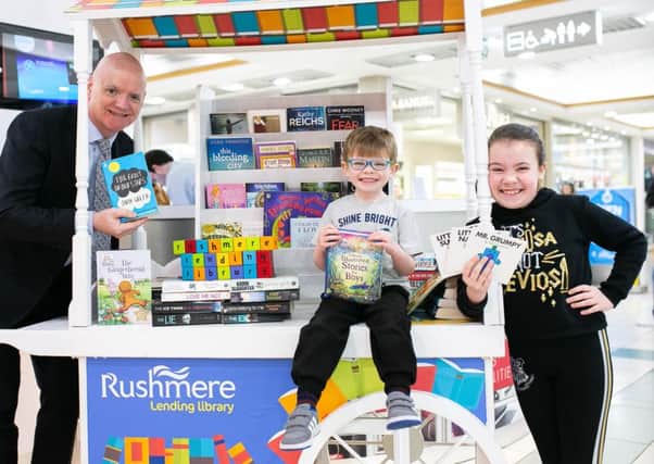 Rushmere Centre Manager, Martin Walsh being helped by Alex, aged 4 and Abigail, aged 9, to launch the Rushmere Lending Library'.