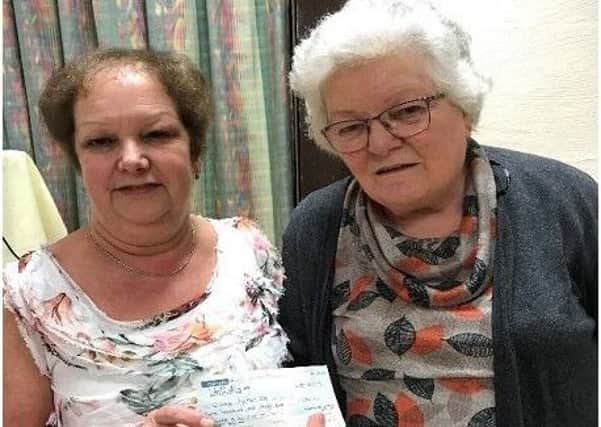 Broughshane WI treasurer Ann McMaster presents a cheque for £435 to Mary Knox BEM at the Institute's recent annual Quiz Night.